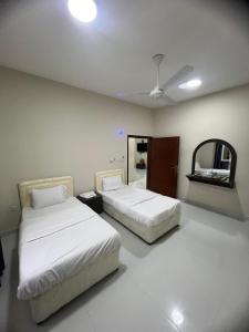 two beds in a room with a ceiling fan at RED algarbeia in Salalah
