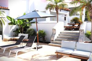 a patio with chairs and an umbrella and palm trees at SOLAR DOS FRADES in Ferreira do Alentejo