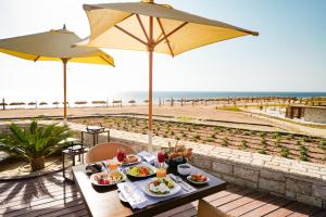 a table with food and an umbrella on the beach at Sentido Reef Oasis Suakin Resort in Marsa Alam City