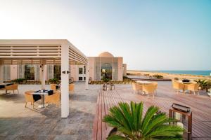 a patio with tables and chairs and the beach at Sentido Reef Oasis Suakin Resort in Marsa Alam City