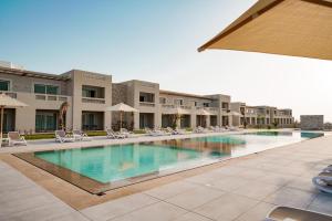 a large swimming pool with chairs and umbrellas at Sentido Reef Oasis Suakin Resort in Marsa Alam City