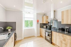 a kitchen with stainless steel appliances and wooden cabinets at Spacious City Apt - Dunfermline in Fife