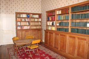 a room with a table and chairs and book shelves at Beau château entre Loire et Bourgogne, 12 chambres 27 personnes in Saint-Doulchard