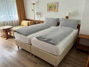 um quarto de hotel com duas camas e uma cadeira em Hotel Adonis em Zermatt