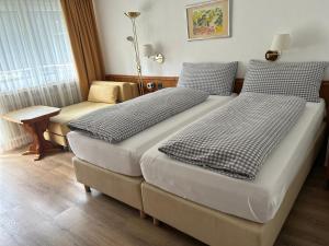 um quarto de hotel com duas camas e uma cadeira em Hotel Adonis em Zermatt