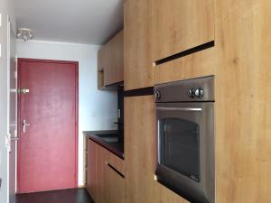 a kitchen with a stainless steel oven and a red door at Studio confortable pour 4 personnes à Arc 1600, proche des pistes - FR-1-411-396 in Arc 1600