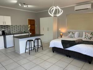 a bedroom with a bed and a kitchen with a counter at Carstens Garden Cottages in Kimberley