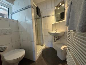 a white bathroom with a toilet and a sink at Zur goldenen Krone Pension Stadtallendorf in Stadtallendorf +13 photos