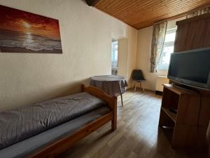 a living room with a bed and a television at Zur goldenen Krone Pension Stadtallendorf in Stadtallendorf