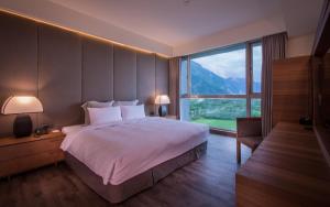 ein Schlafzimmer mit einem großen Bett und einem großen Fenster in der Unterkunft Taroko Liiko Hotels in Xincheng