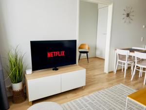 a living room with a tv on a white cabinet at City Apartment with lake view and free parking in Kuopio