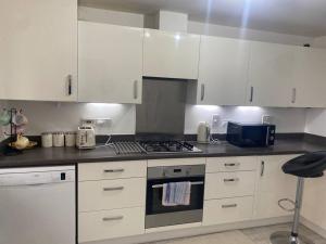 a kitchen with white cabinets and a stove top oven at Liddle Way Garden Getaway in Basingstoke