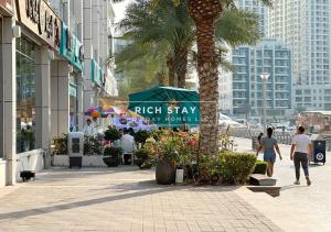 people walking down a sidewalk in a city with a palm tree at Harmonious 3BR in Stella Maris, Sea View, Marina in Dubai