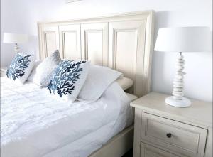 a white bed with pillows and a lamp on a night stand at Dickenson Bay Oasis at Antigua Village in Saint Johnʼs