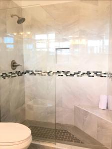 a bathroom with a toilet and a glass shower at Dickenson Bay Oasis at Antigua Village in Saint Johnʼs