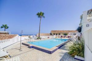 a swimming pool with a palm tree and a building at The lighthouse horizon in Las Lagunas Mijas