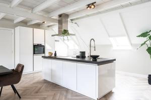 a kitchen with white cabinets and a black counter top at Xxl Loft City Center Villa Tilburg Willem 2 in Tilburg