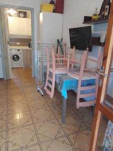 a kitchen with a table with chairs and a television at trilocale sul mare con giardino privato in Sorso