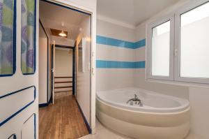 a white tub in a bathroom with blue and white stripes at Maison de vacances 50m de la plage in Larmor-Plage +17 photos