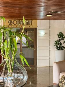 a glass vase sitting on a table with a plant at Uberaba Hotel Suítes in Uberaba