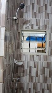 Un baño con ducha con espejo y ventana. en Bonamoussadi Gardens - Piscine-Wifi- Eau- Electricite 24h sur 24, en Douala