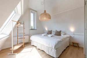 デ・ハーンにあるHuswell - Beautiful home for 14 guests , pets are welcomeの白いベッドルーム(ベッド1台、ランプ付)