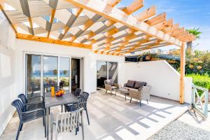 eine Terrasse mit einer hölzernen Pergola sowie einem Tisch und Stühlen in der Unterkunft Villa Wave Blue by Ezoria Villas in Klorakas