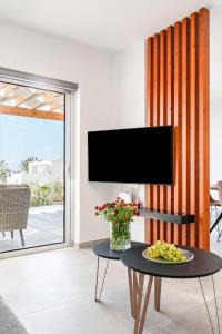 ein Wohnzimmer mit Fernseher und Tisch in der Unterkunft Villa Wave Blue by Ezoria Villas in Klorakas