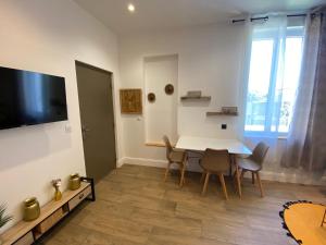 a living room with a table and chairs and a tv at Maison de ville in Fenouillet
