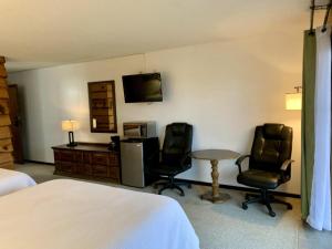 a hotel room with a bed and two chairs and a table at Bridge Inn Tomahawk - 2nd Floor, 2 Queen Beds, Balcony, River View in Tomahawk