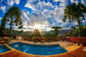a swimming pool with the sun in the background at Prime Estúdios Campos - 1,2 km do Centro Turístico Capivari in Campos do Jordão