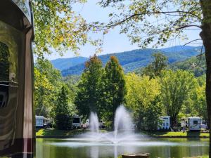 a fountain in a pond with mountains in the background at Water Edge Glamping Resort- Fishing Pond, Fire Pit, Mini Golf, Golf Cart in Gatlinburg