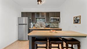 a kitchen with a counter with chairs and a refrigerator at Casita 3 at Ceiba Tree Inn. Tranquility with Garden Views and Pergola with Ocean Overlook in Rincon +10 photos