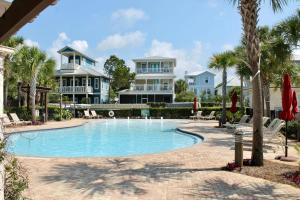 a pool with chairs and palm trees in front of houses at Seacrest - The Wellington in Panama City Beach