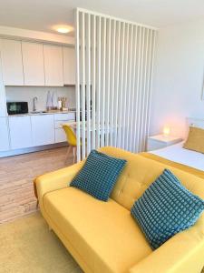 a living room with a yellow couch with two blue pillows at Domus da Ria - Alboi III in Aveiro