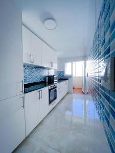 a kitchen with white cabinets and blue tiles on the wall at Mar Menor Paradise by Los Pinos Holidays in San Pedro del Pinatar