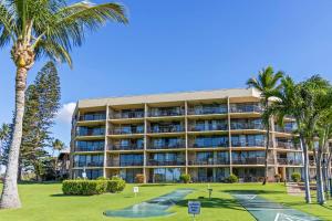 a large building with palm trees and a golf course at Maui Sunset A413 in Kihei
