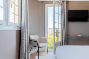 a room with a white chair and a window at Maison Bérard Hôtel - Restaurant - Spa in La Cadière-dʼAzur