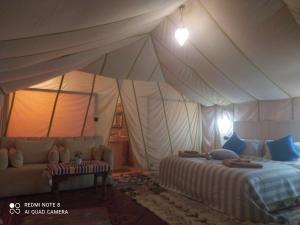 a bedroom with a tent with a bed and a couch at Berber Camp Merzouga in Merzouga