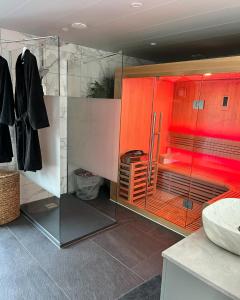 a bathroom with a glass shower with red lighting at Ladetentethailan in Vicq