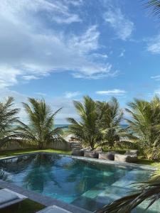 a swimming pool with palm trees and the ocean at Beach House Brazil in Amontada