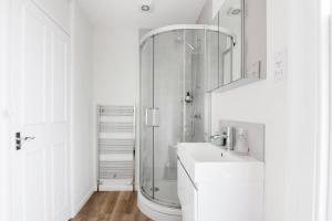 a white bathroom with a shower and a sink at Charlotte Street Apartment in Bath