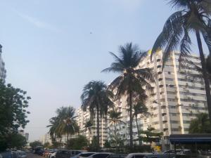 ノンタブリーにあるAsia Don Mueang Bangkok Condominiumのヤシの木が前に生えている大きな建物