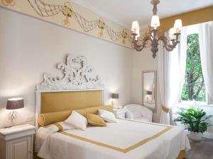Un dormitorio con una cama grande con sábanas blancas y una lámpara de araña. en Hotel Villa Maremonti en Marina di Massa