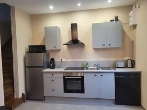 a kitchen with white cabinets and a black refrigerator at O Bel Haybois Dormant " Le Cerf " in Haybes