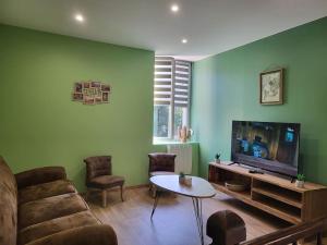 a living room with a couch and a tv and a table at O Bel Haybois Dormant " Le Cerf " in Haybes