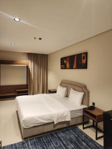 a bedroom with a white bed and a television at المهيدب للشقق الفندقية in Rabigh