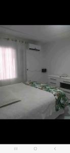 a bedroom with a large white bed with a window at Casa cataratas 3 in Foz do Iguaçu