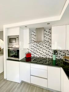 a kitchen with white cabinets and a black counter top at Guesthouse Santos & Belos in Nazaré +14 photos