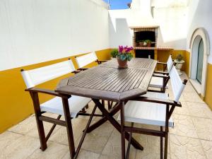 a wooden table and chairs on a balcony with a fireplace at Guesthouse Santos & Belos in Nazaré